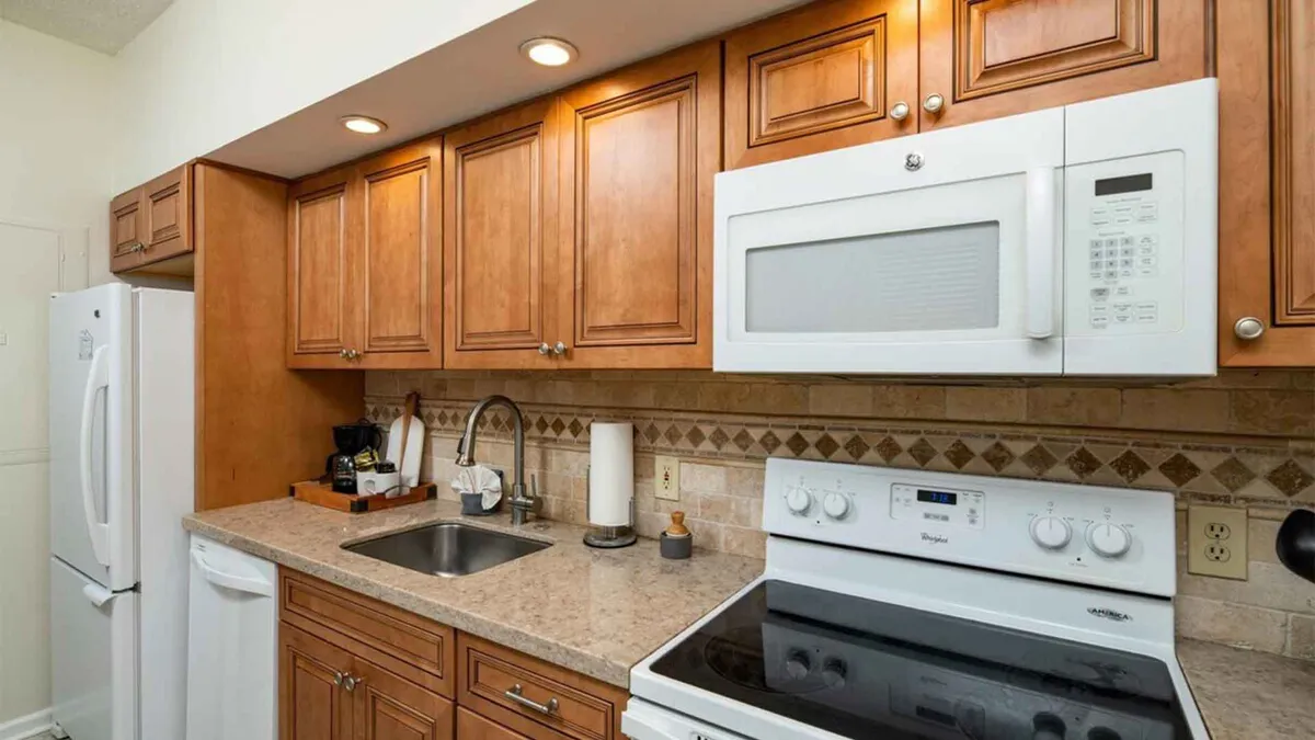 A beautifully renovated kitchen with warm wooden cabinetry, sleek stainless steel appliances, granite countertops, and a stylish tile backsplash. The space exudes a welcoming atmosphere, ideal for cooking and baking, and is designed to accommodate family gatherings and meal preparation.