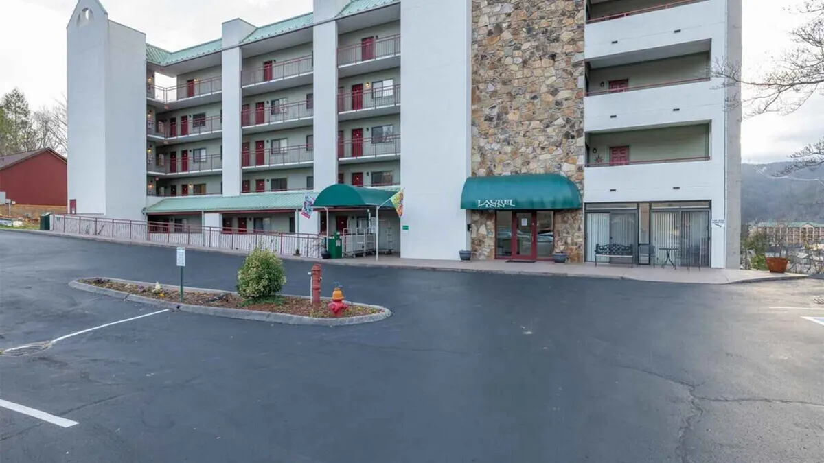 The main entrance of the condo property, featuring an attractive stone facade, green awning, and convenient parking area. The entrance feels welcoming, suggesting easy access to both the property and the nearby attractions.