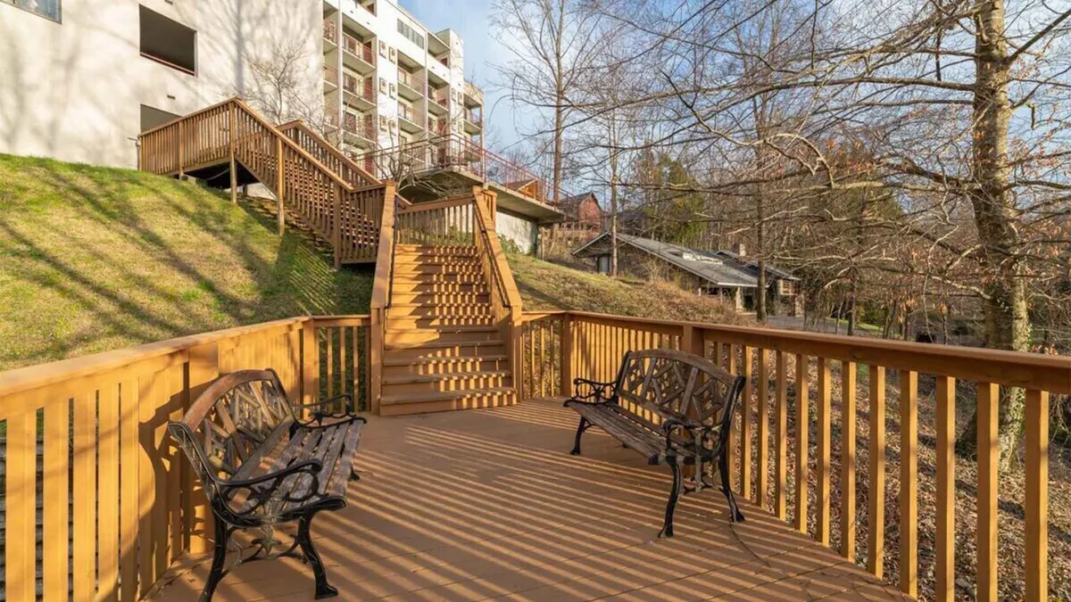 A tranquil wooden deck nestled among tall trees, complete with benches and a staircase leading into nature. The setting is ideal for relaxing after a day of adventure, socializing with friends, or simply soaking in the sunset and stargazing at night.