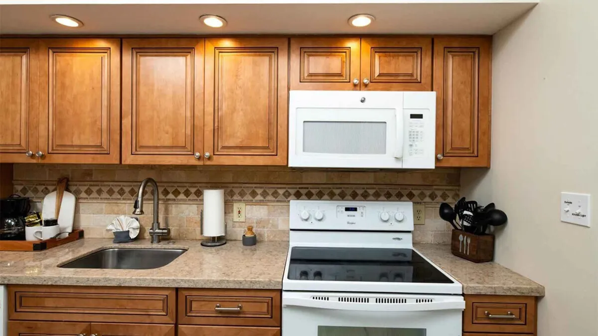 A cozy kitchen with wooden cabinetry, a granite countertop, white appliances, and a sink. The scene is perfect for cooking, meal preparation, and entertaining guests, highlighting the kitchen's functional design and homey atmosphere.